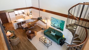 A spacious living area with a dining table, sofa, and a spiral staircase.