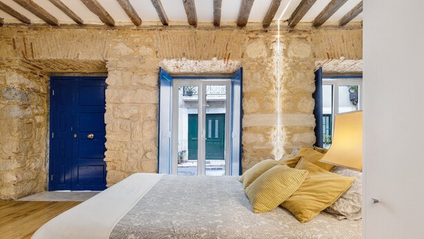 A bedroom with a bed, a blue door, and a window with a view. - Beautiful Loft “Green Street Lisbon” in City Centre with Wi-Fi & A/C (Lisboa)