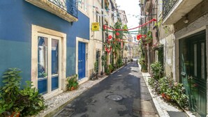 A narrow street with buildings on either side, some with balconies and potted plants. - Beautiful Loft “Green Street Lisbon” in City Centre with Wi-Fi & A/C (Lisboa)