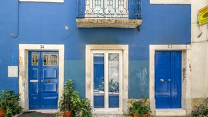 A building with blue doors numbered 34 and 32, a balcony with metal railings, and potted plants on the ground. - Beautiful Loft “Green Street Lisbon” in City Centre with Wi-Fi & A/C (Lisboa)