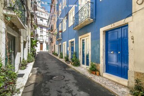 A narrow street with buildings on either side, featuring blue doors and balconies with plants. - Beautiful Loft “Green Street Lisbon” in City Centre with Wi-Fi & A/C (Lisboa)