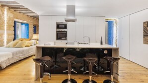A compact kitchen with a central island, bar stools, and a bed with a view. - Beautiful Loft “Green Street Lisbon” in City Centre with Wi-Fi & A/C (Lisboa)
