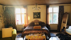 Ein gemütliches Schlafzimmer mit einem großen Bett, einem Holz-Kopfteil, einer Chandelier und einem Fenster mit Vorhängen.