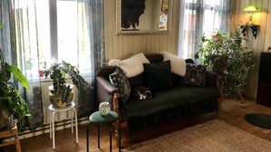 Ein gemütliches Wohnzimmer mit einer Couch, einem kleinen Tisch und verschiedenen Pflanzen.