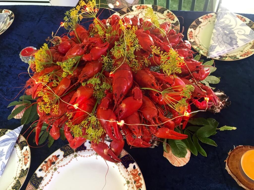 A table with a large arrangement of red crayfish garnished with greenery.