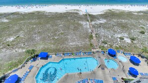 Un complexe hôtelier de bord de mer doté de plusieurs piscines, de parasols et de chaises longues.