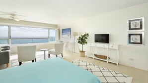 Une chambre moderne avec un lit, un bureau, une télévision et une vue sur l’océan.