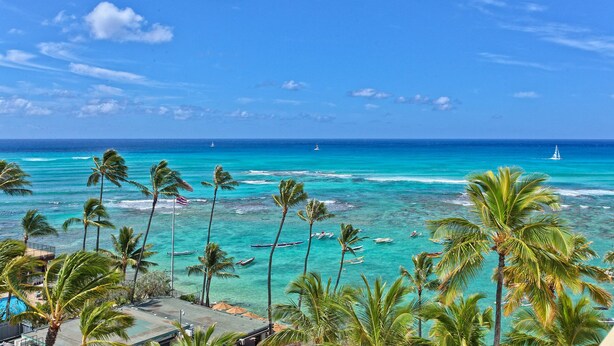 Une plage tropicale aux eaux turquoise et limpides, bordée de palmiers, avec une vue imprenable sur l’océan.