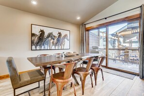 A dining area with a large table, six chairs, and a painting of horses on the wall.