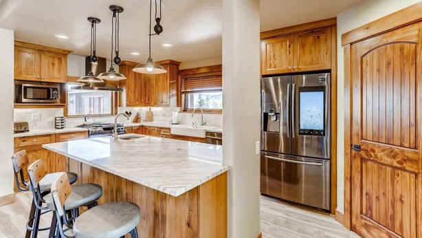 Una cocina moderna con armarios de madera, electrodomésticos de acero inoxidable y una isla central con taburetes de bar.