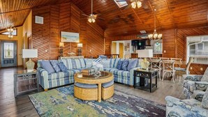 Ein geräumiges Wohnzimmer mit einer großen Eckcouch, einem runden Couchtisch und einem Essbereich mit Tisch und Stühlen.