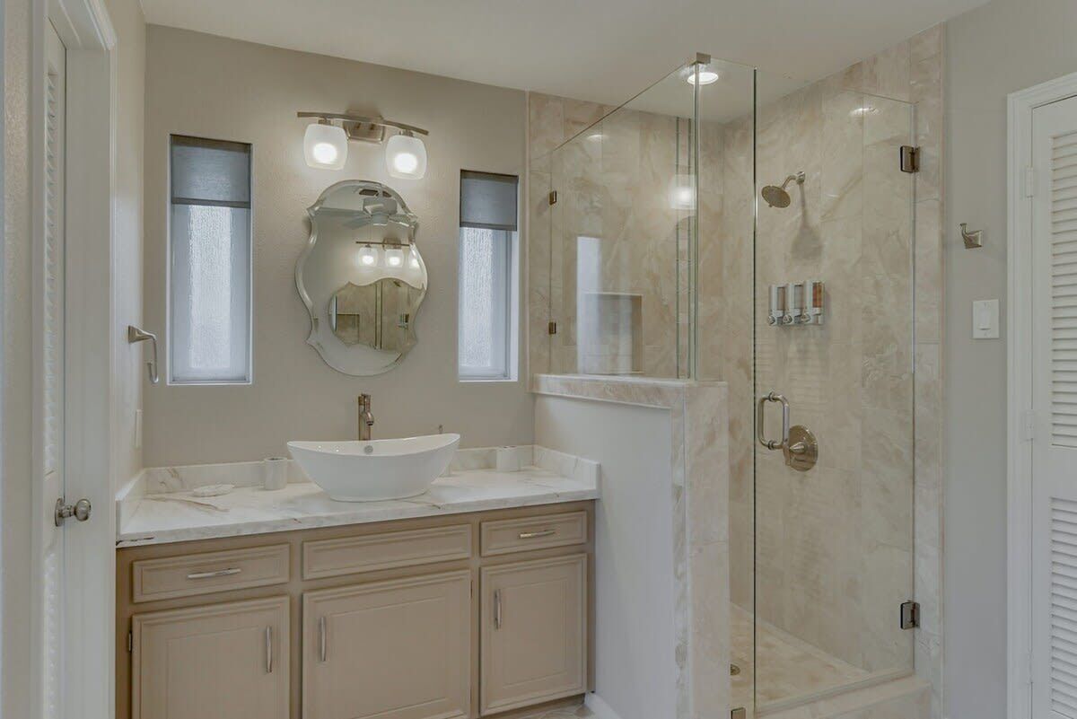 A modern bathroom with a large sink, a glass shower enclosure, and a wall-mounted mirror.