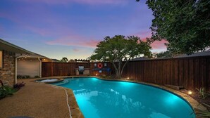Un jardin avec une piscine, un espace barbecue et une clôture en bois.