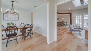 Un vaste espace dédié à la salle à manger, avec une table et des chaises en bois, un lustre et un mur orné d’une citation inspirante.
