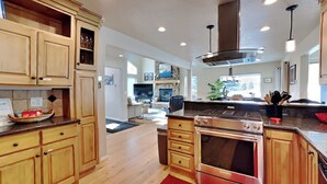 Une cuisine moderne avec des meubles en bois, un four encastré et une cheminée en pierre.