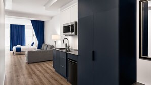 Een moderne hotelkamer met een bed, een bank, een kitchenette met een magnetron en een ruime garderobe.