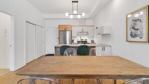 Una cocina moderna con una mesa de comedor de madera, sillas transparentes y una lámpara colgante.