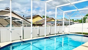 Ein Schwimmbecken mit weißem Zaun und einer überdachten Liegefläche.