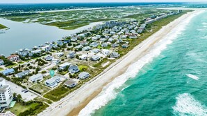 An aerial view of a coastal residential area with houses along the beachfront, a marina, and a large body of water. - Experience island life with amazing views and easy beach access! 6BR, 5BA (Wrightsville Beach)