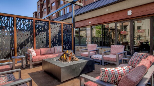 An outdoor seating area with sofas and chairs, a fire pit, and a view of a building with a 'NO Access' sign.