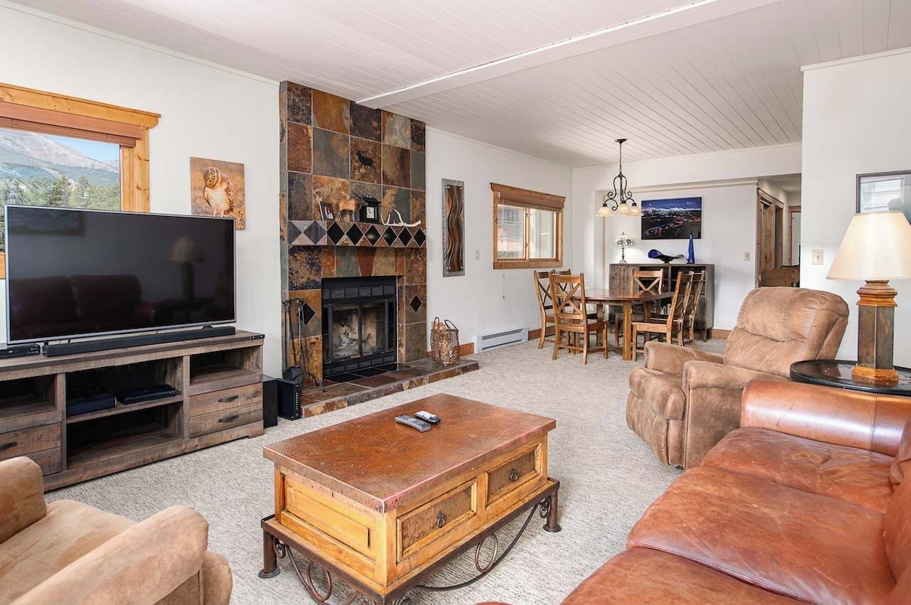 A living room with a fireplace, a television, and leather furniture.