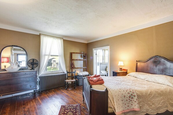 A bedroom with a wooden bed, a dresser, a radiator, a chair, and a window with curtains. - Fall Foliage Getaway: Pocono Home by Lehigh Gorge (White Haven)