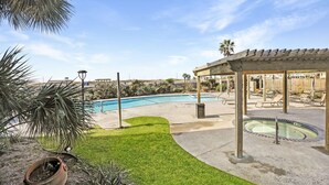 A swimming pool area with a gazebo, a hot tub, and a grassy lawn.