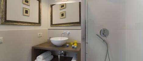 A bathroom with a sink, mirror, and shower.