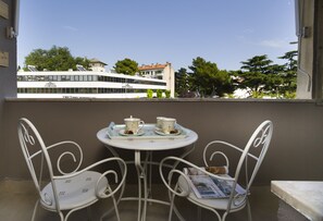 A balcony with two white metal chairs, a small round table, and a tray with two teacups and saucers. -  Il Verde, Two Bedroom Apartment with Two Bathrooms (Split)