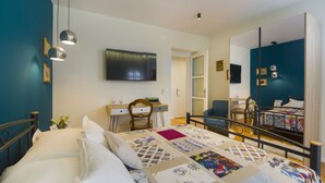 Un dormitorio bien iluminado con una cama grande, un escritorio, una silla, un espejo y un televisor.