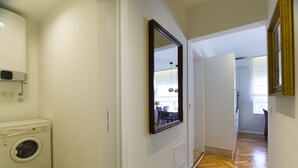 Un pasillo con lavadora, espejo y puerta que da a otra habitaci ón.
