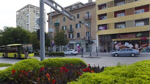 Una calle con un autobús, coches y un edificio con un cartel que dice "RIVIERA AUTOMAT KLUS".