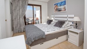 A bedroom with a bed, bedside tables, a desk, and a painting on the wall.
