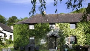 A house with ivy-covered walls, a stone entrance, and a well-maintained lawn.