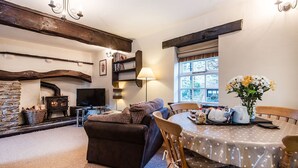 A cozy living room with a fireplace, a television, and a dining area with a table set for two. - A delightful two bedroom cottage with exceptional indoor leisure facilities (Boncath)