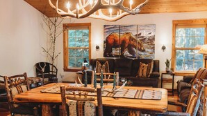 Un comedor rústico con una mesa de madera, sillas y una araña.