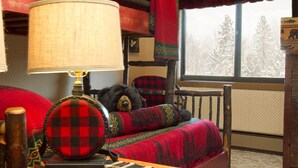 A cozy room with a bed, a lamp, and a window with a view of trees.