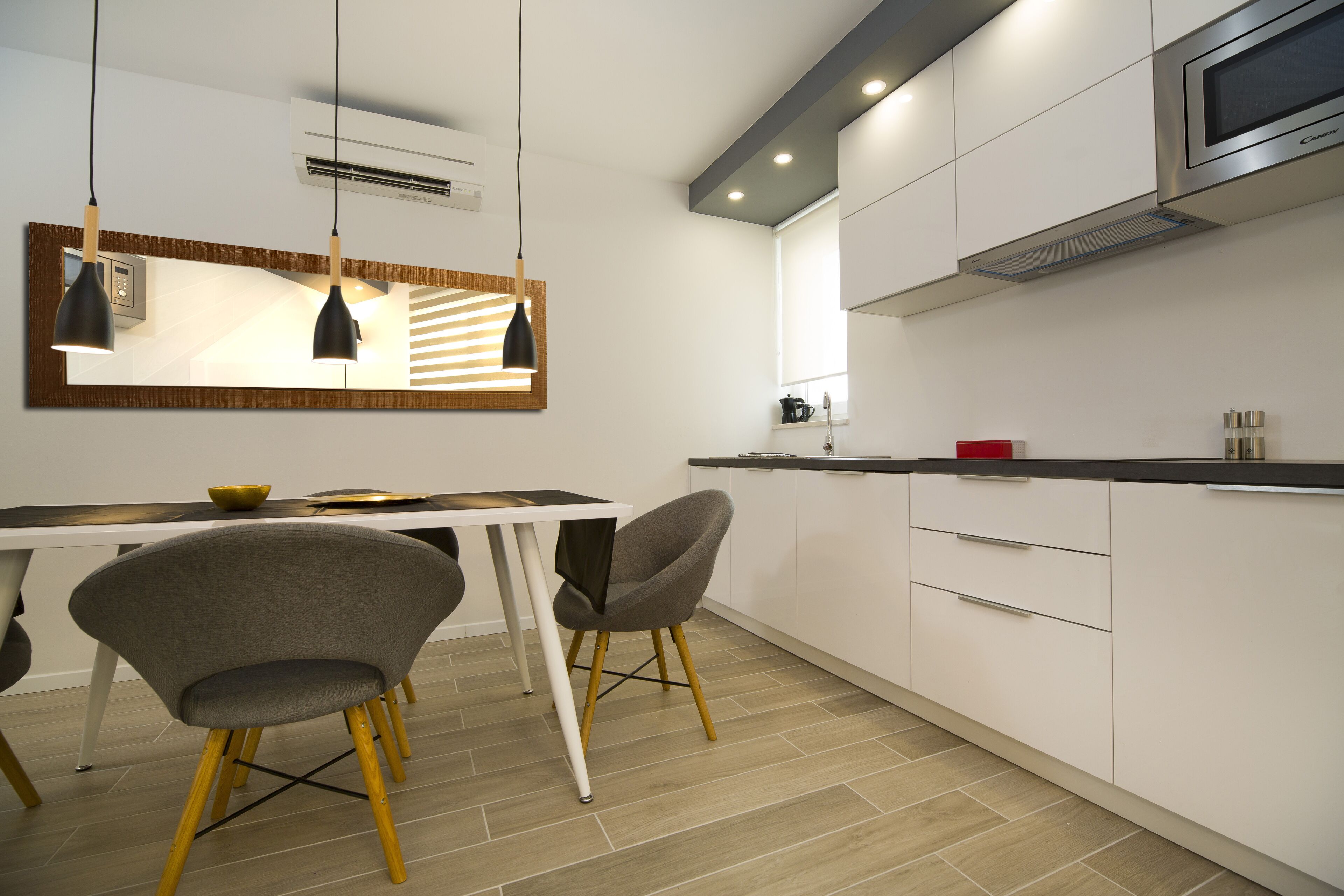 A modern kitchen with white cabinets, a stainless steel microwave, and two pendant lights.