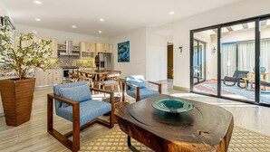 Una sala de estar moderna con una mesa de centro de madera, sillas tapizadas en azul y un amplio ventanal con vistas al exterior.