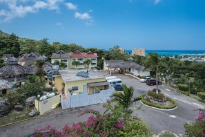 A resort with multiple buildings, a parking area, and a view of the ocean.