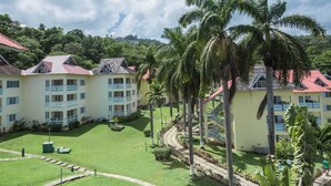A hotel with multiple buildings, a well-maintained lawn, and palm trees. - Mystic Ridge Resort (Ocho Rios)