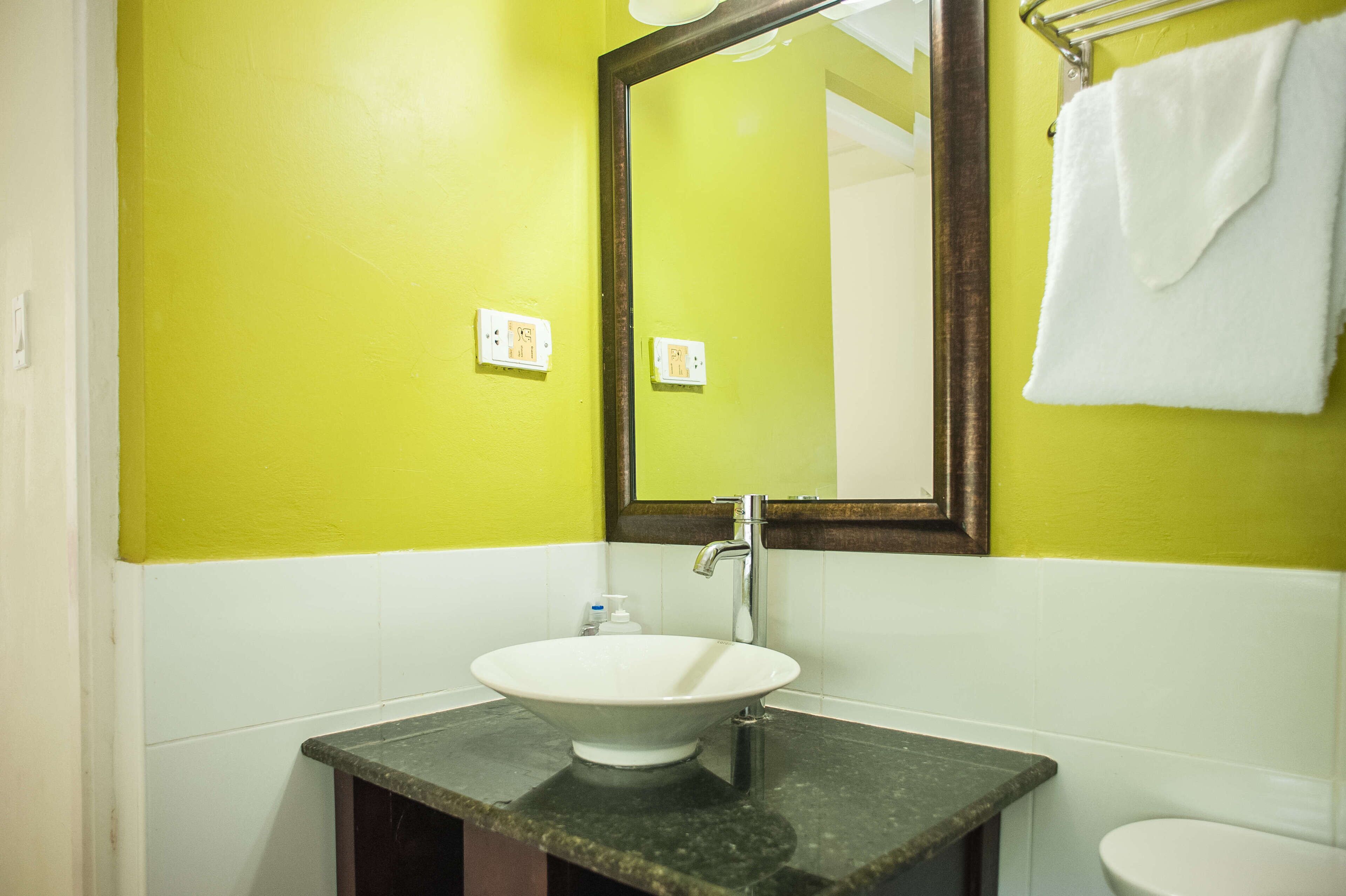 A bathroom with a white sink, a mirror, and a towel hanging on a rack.