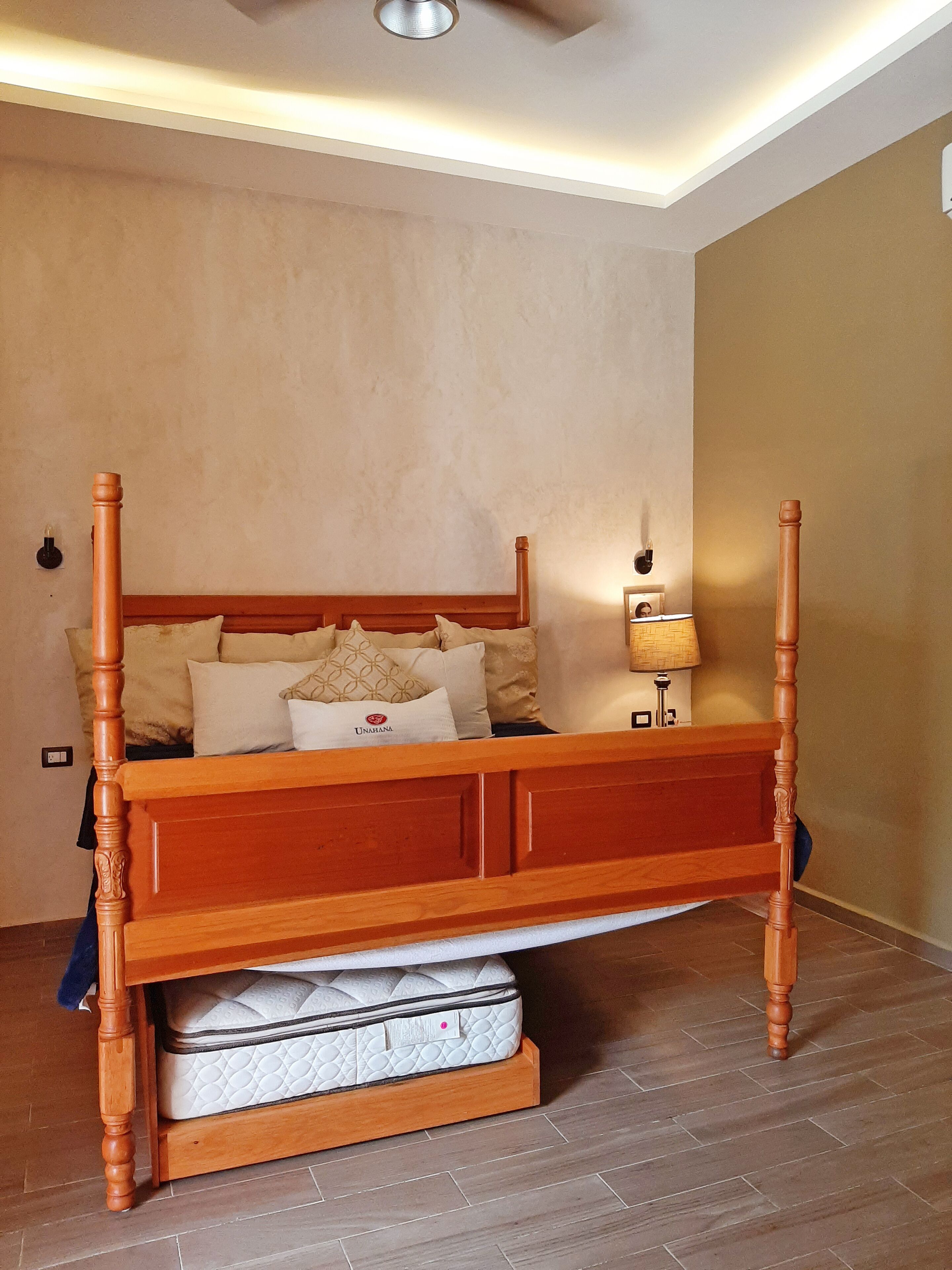 Ein Himmelbett mit Holzgestell und einer Matratze darunter.