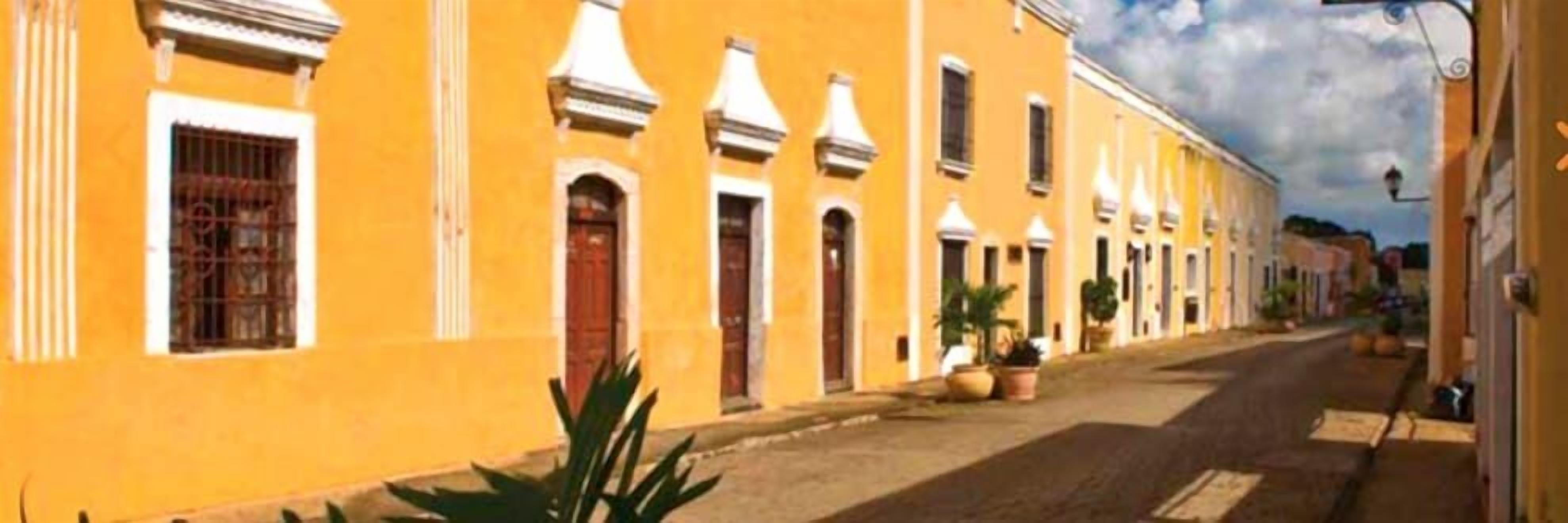 A street lined with yellow buildings, featuring uniform architecture and a clear road.