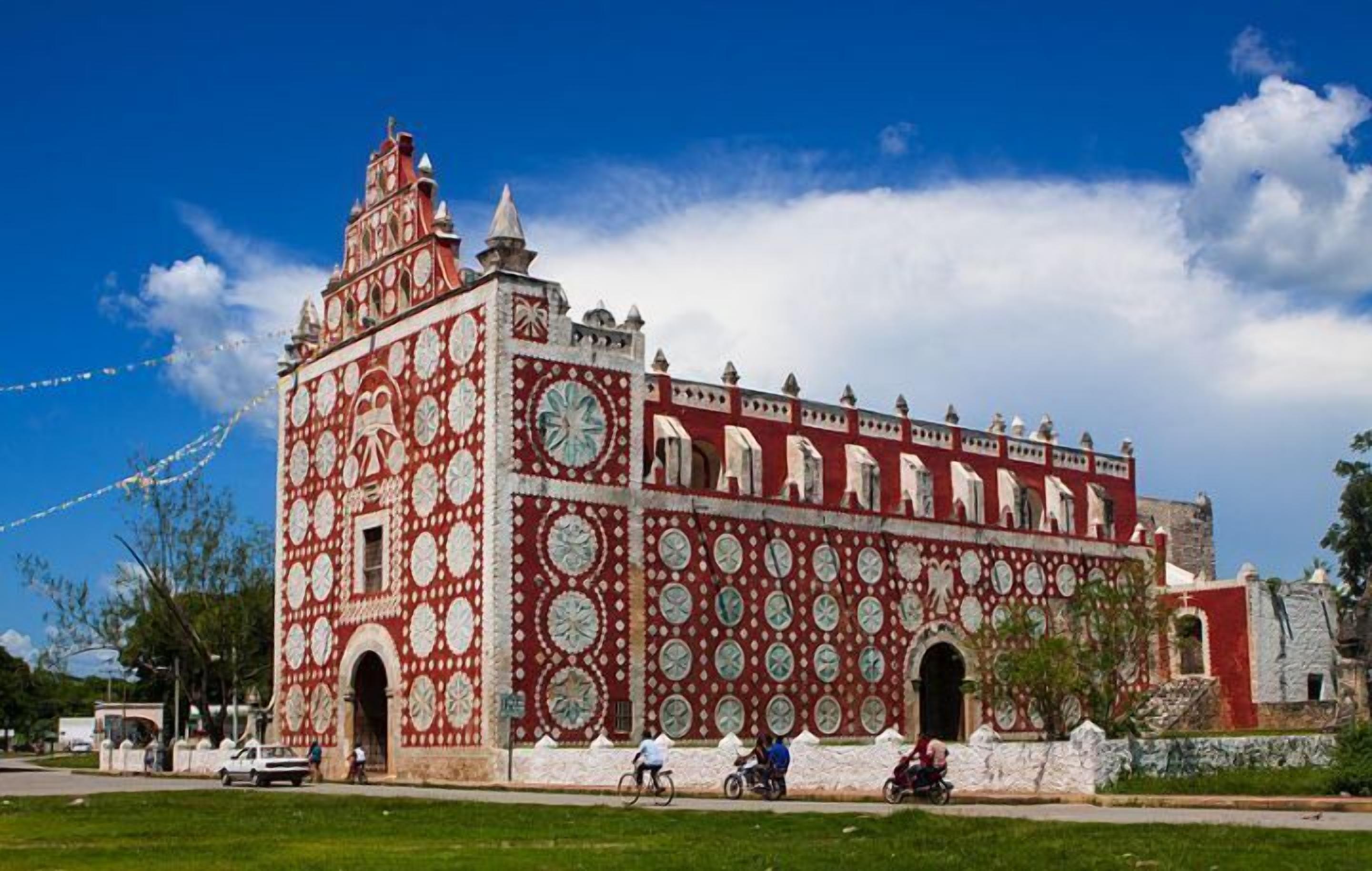 A large building with a red and white facade, multiple arched windows, and a clock tower.