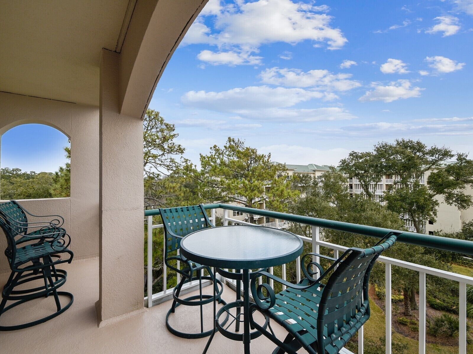 Un balcon avec une table ronde et deux chaises, entouré d’une balustrade.