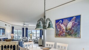 Et spiseområde med et rundt hvidt bord, hvide stole og en lysekrone.