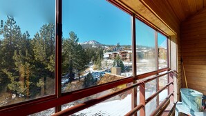 A wooden cabin with large windows overlooking a snowy mountain and a small town. - Aspen 230-Walking distance to the ski area with views of Mammoth Mountain! (Mammoth Lakes)