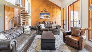 A modern living room with leather sofas, a coffee table, and a wooden accent wall. - Aspen 230-Walking distance to the ski area with views of Mammoth Mountain! (Mammoth Lakes)