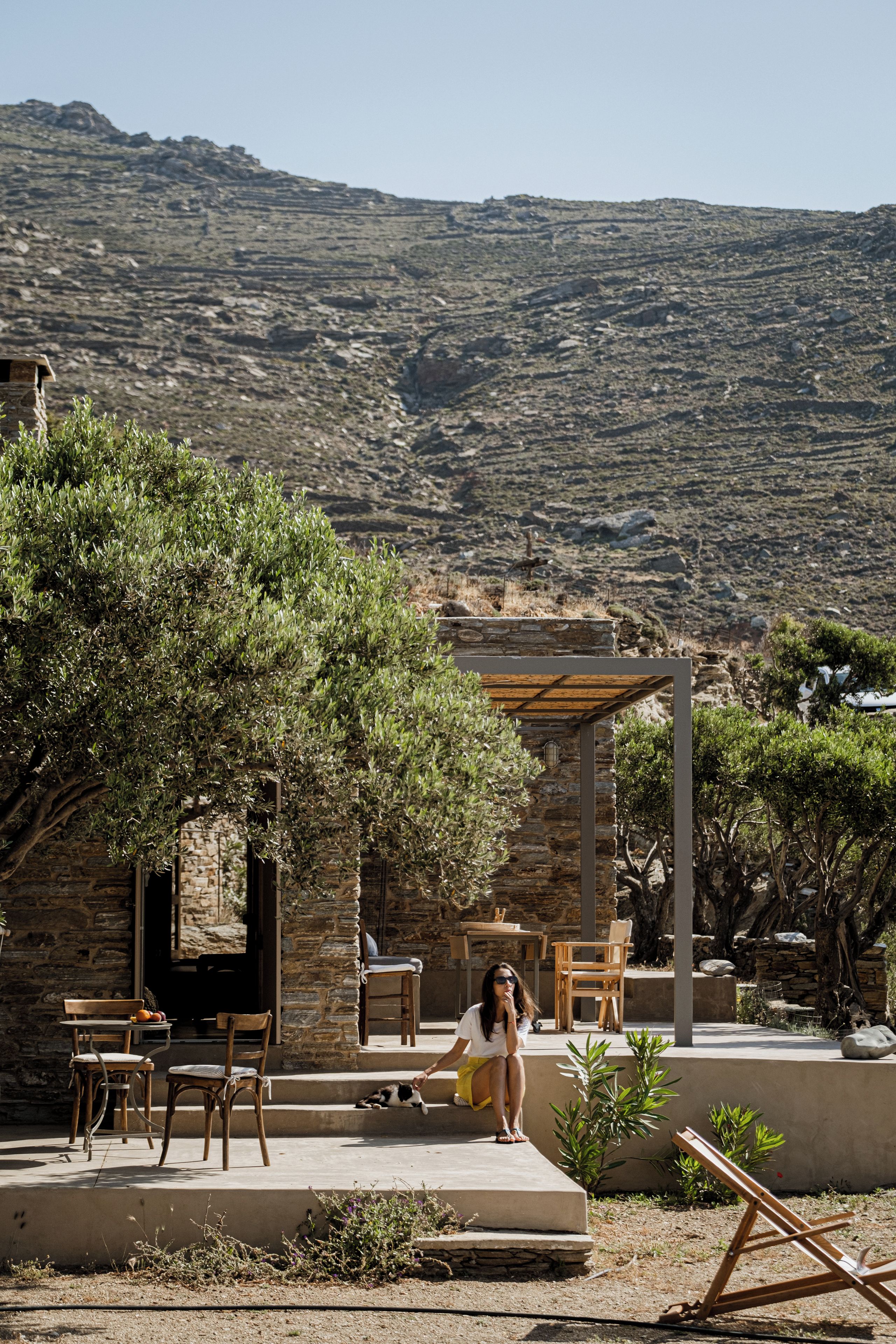 Un espacio de estar al aire libre rústico con paredes de piedra, muebles de madera y vistas a un paisaje montañoso.